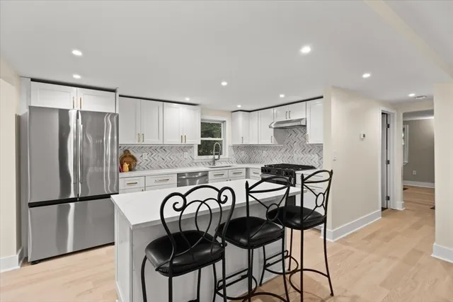 a kitchen with granite countertop a refrigerator and a stove top oven