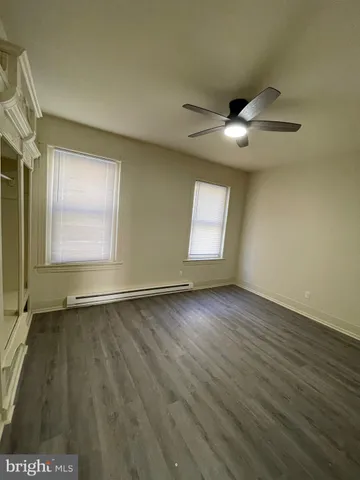 an empty room with wooden floor chandelier fan and windows