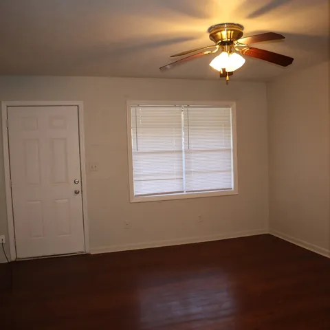 a view of a livingroom with a fan a hardwood floor and a chandelier