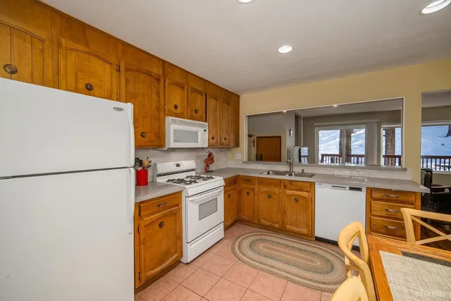 a kitchen with granite countertop a stove a sink a refrigerator and a dining table with wooden floor