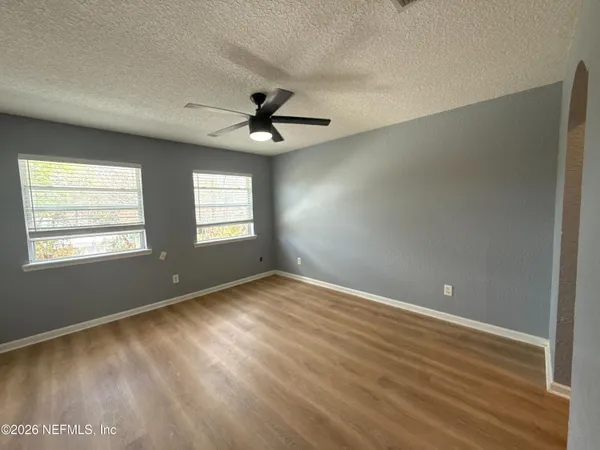 a view of an empty room with window and wooden floor