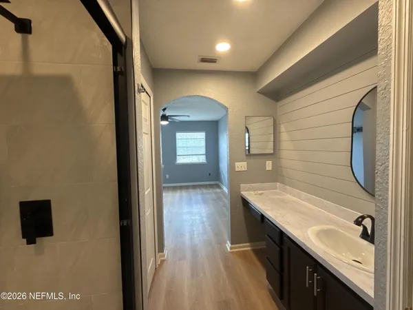 a bathroom with a granite countertop sink a mirror and shower