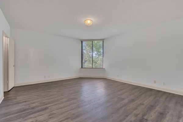 a view of an empty room with wooden floor and closet