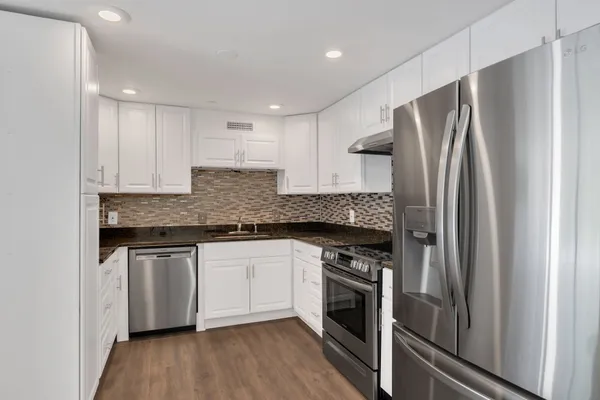 a kitchen with granite countertop white cabinets and white appliances