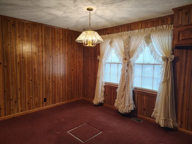 a view of a livingroom with a chandelier curtains and large windows