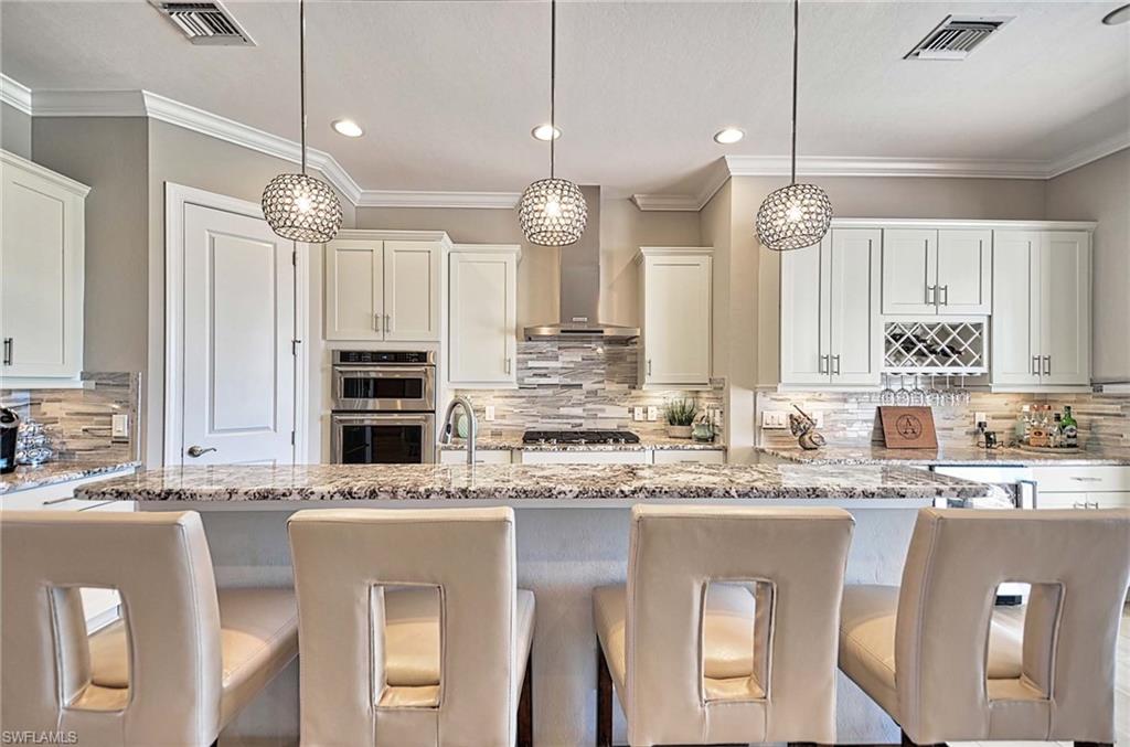 2166 Antigua Lane Naples, FL 34120 - Photo 5 of 35 a kitchen with kitchen island granite countertop a sink cabinets and stainless steel appliances