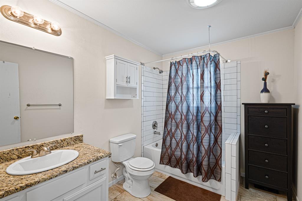 818 Country Club Road Bowie, TX 76230 - Photo 24 of 34 a bathroom with a granite countertop sink toilet a mirror and shower