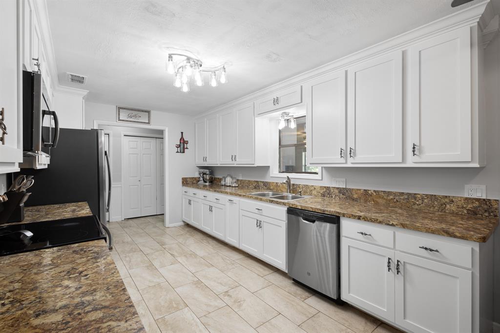 818 Country Club Road Bowie, TX 76230 - Photo 7 of 34 a kitchen with granite countertop white cabinets and stainless steel appliances