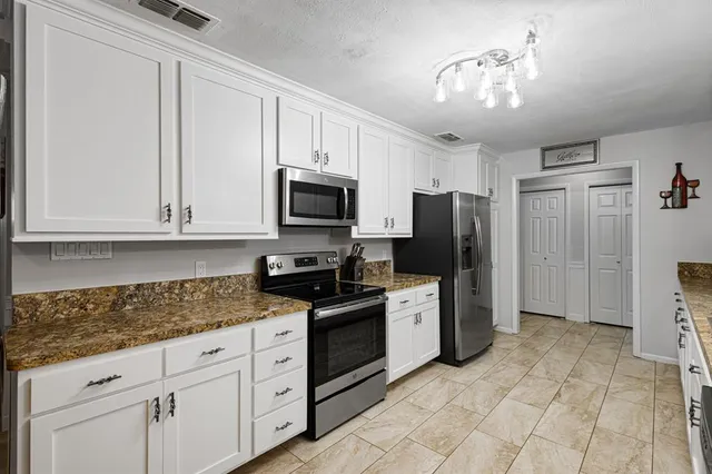 a kitchen with stainless steel appliances granite countertop a refrigerator and cabinets