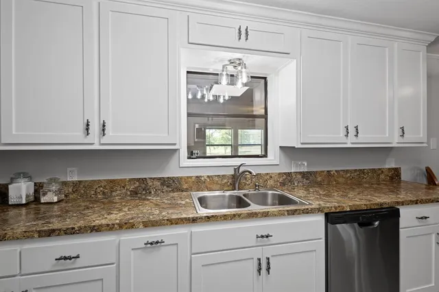 a kitchen with granite countertop white cabinets and a sink