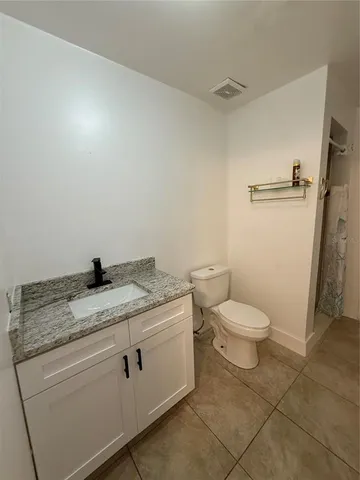 a bathroom with a granite countertop toilet and a sink