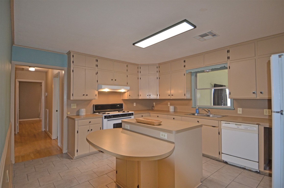 2352 Airport Road Brenham, TX 77833 - Photo 10 of 24 a kitchen with a sink a stove a refrigerator and white cabinets