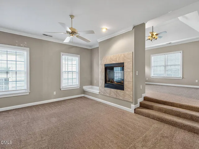 an empty room with windows and fireplace