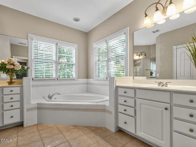 a spacious bathroom with double vanity sink a two mirror a bathtub a vanity and a bathtub