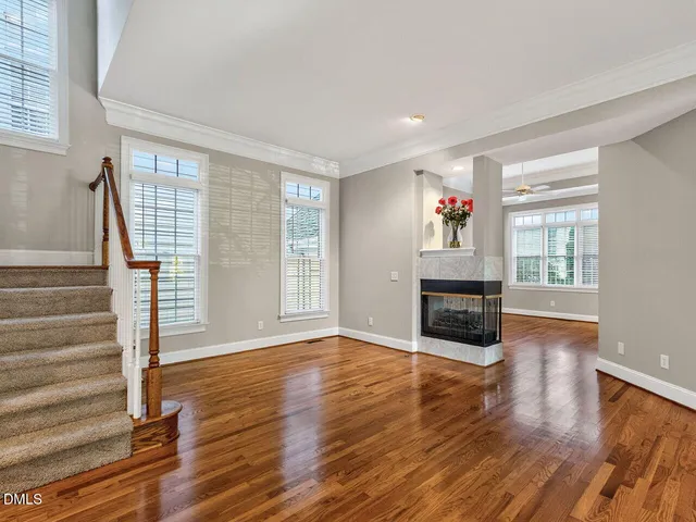 a view of an empty room with wooden floor fireplace and a window