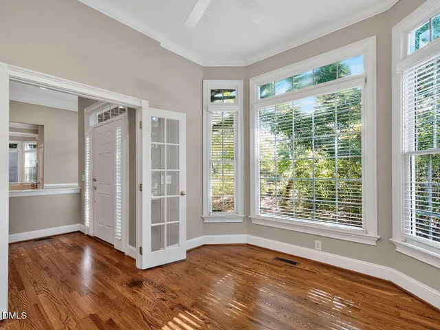a view of an empty room with wooden floor and a window
