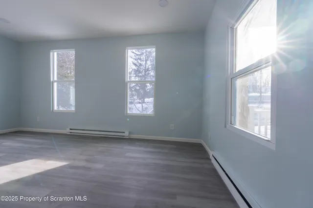 a view of an empty room with wooden floor and fence