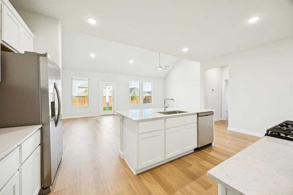9509 Rattlesnake Trail Crowley, TX 76036 - Photo 10 of 35 a large white kitchen with a refrigerator a sink dishwasher a stove and a dining table with wooden floor