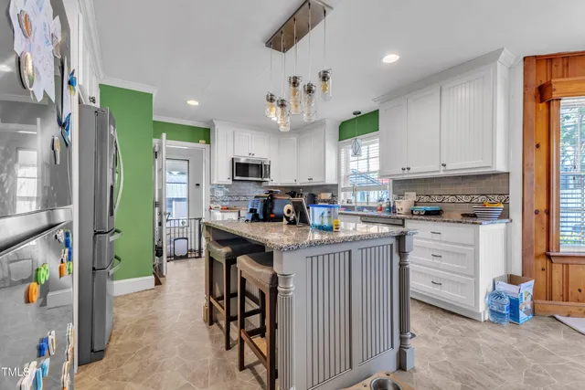 a kitchen with kitchen island granite countertop a stove a sink and a refrigerator