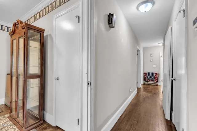 a view of a hallway with wooden floor and a bathroom