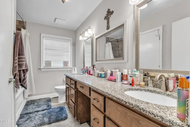 a bathroom with a granite countertop sink a toilet a mirror and shower