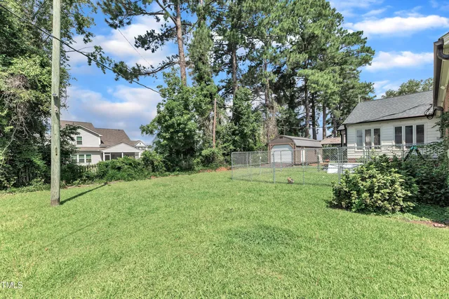 a view of a house next to a big yard and large trees