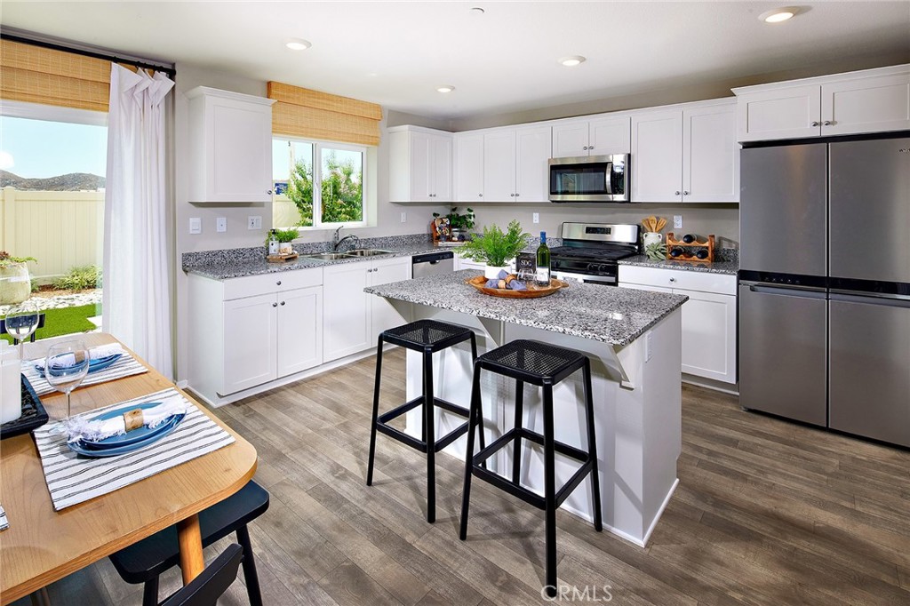 30607 Cyclone Avenue Winchester, CA 92596 - Photo 5 of 18 a kitchen with stainless steel appliances granite countertop a refrigerator a stove a sink a dining table and chairs with wooden floor