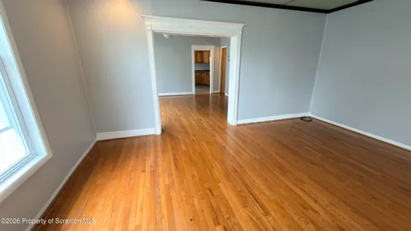 a view of an empty room with wooden floor and a window