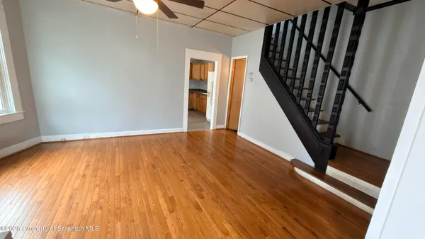 a view of an empty room with wooden floor and stairs