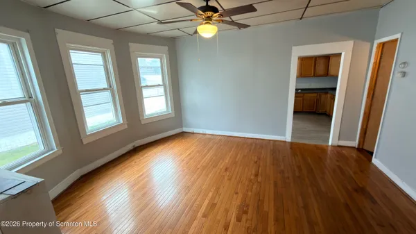 a view of an empty room with wooden floor and a window