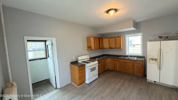a kitchen with a stove a refrigerator and a wooden floor