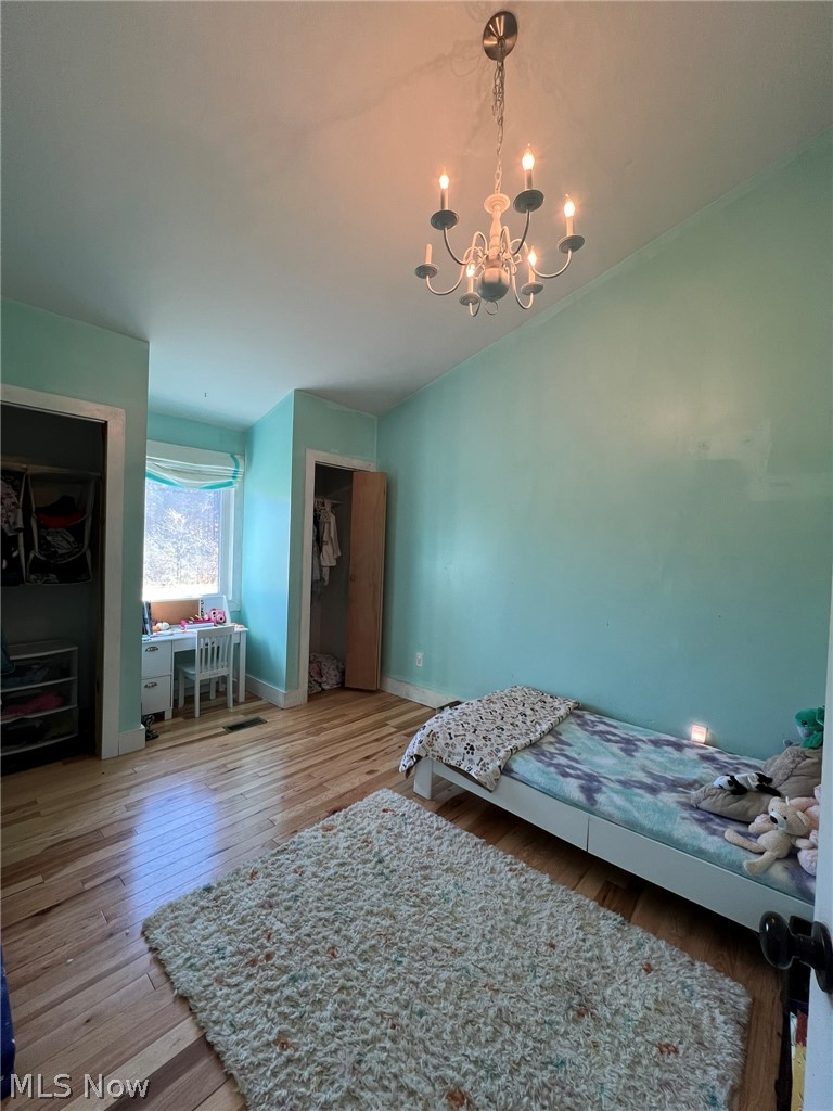 15393 Shade Road Guysville, OH 45735 - Photo 10 of 35 Spacious interior room featuring light wood-finish flooring, a contemporary chandelier, two built-in closet spaces, and a window with natural light
