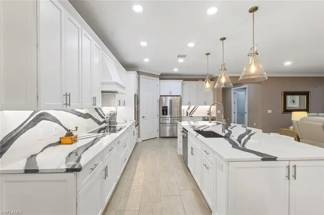 a view of a kitchen with kitchen island stainless steel appliances a sink and a wooden floor