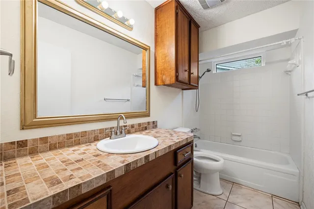 a bathroom with a granite countertop sink toilet and shower