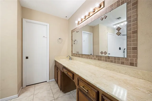 a spacious bathroom with a granite countertop sink and a mirror