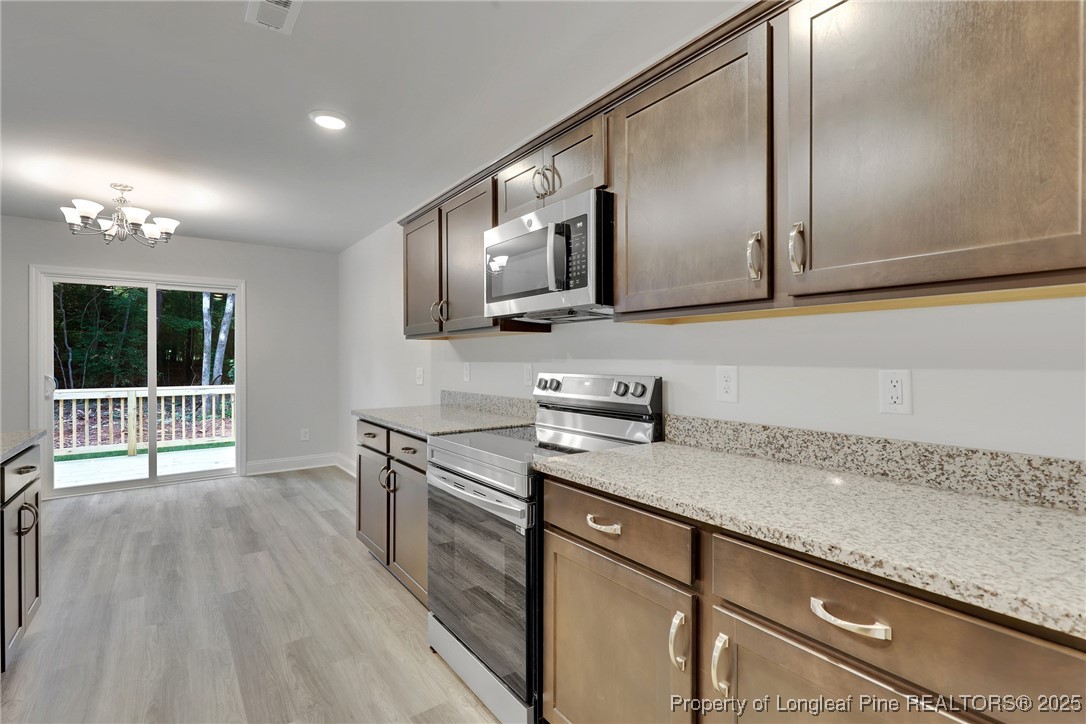 1036 Meadow Reach Sanford, NC 27332 - Photo 5 of 30 a kitchen with granite countertop a sink a stove and cabinets