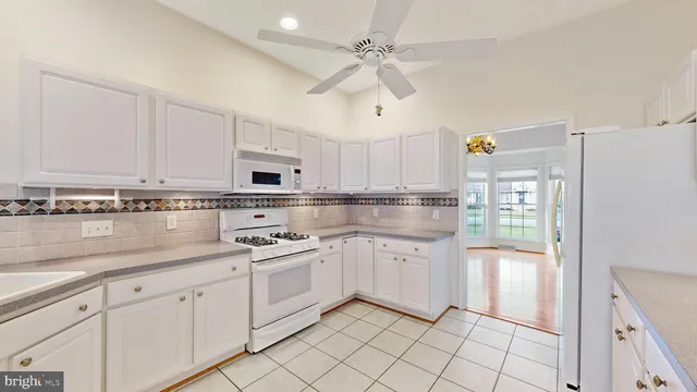 an empty room with chandelier fan and windows