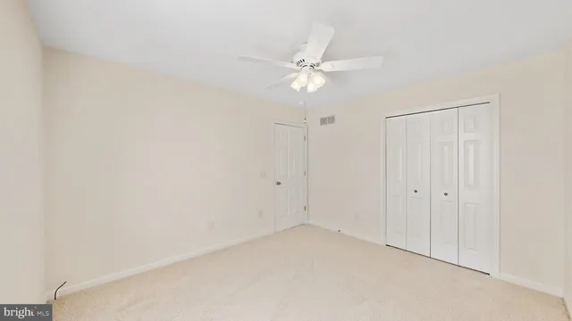 an empty room with closet and ceiling fan