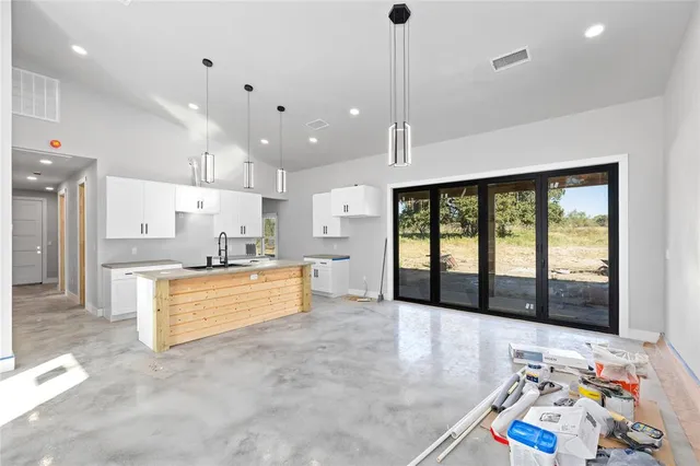 a large kitchen with stainless steel appliances kitchen island a large counter top and a wooden floors