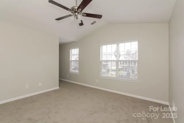 an empty room with windows and fan