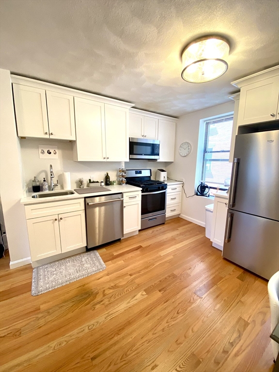 a kitchen with a refrigerator a stove top oven a sink and dishwasher with wooden floor