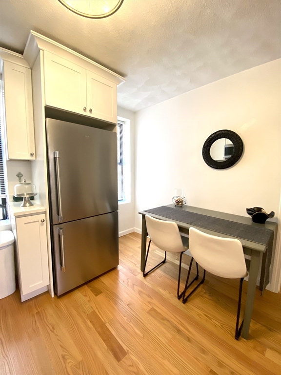 24 Charter Street, Unit 3 Boston, MA 02113 - Photo 3 of 9 a living room with a table chairs and a refrigerator