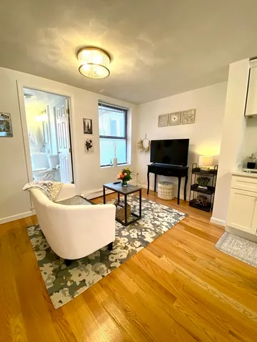 a living room with couches and a flat screen tv with kitchen view