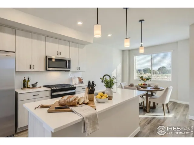 a kitchen with stainless steel appliances kitchen island granite countertop a stove a sink a dining table and chairs with wooden floor