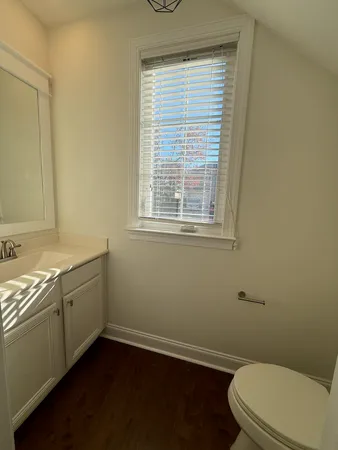 a bathroom with a granite countertop toilet a sink and a window
