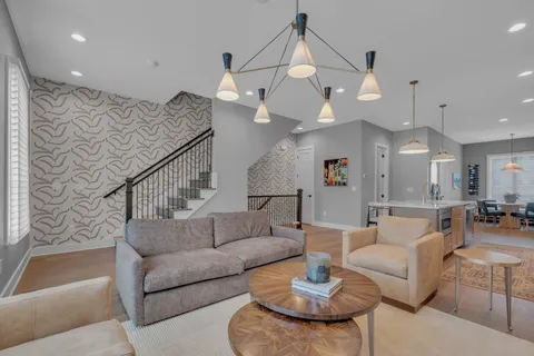 a living room with furniture kitchen view and a chandelier