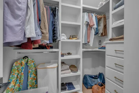 a view of walk in closet with clothes and shoes