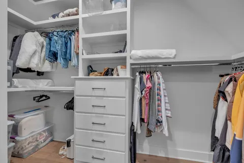 a view of walk in closet with clothes and shoes