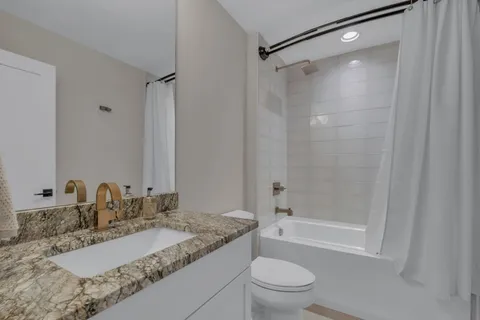 a bathroom with a granite countertop sink toilet and shower