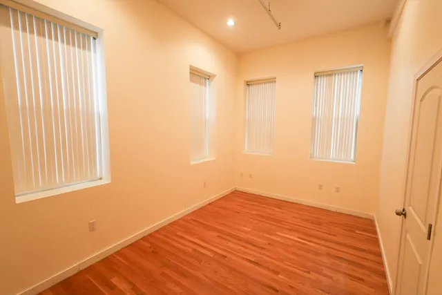 a view of empty room with wooden floor and fan